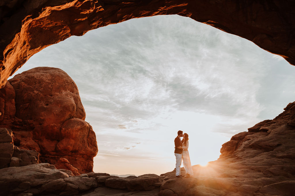 couple kisses at Arches National Park sunset elopement