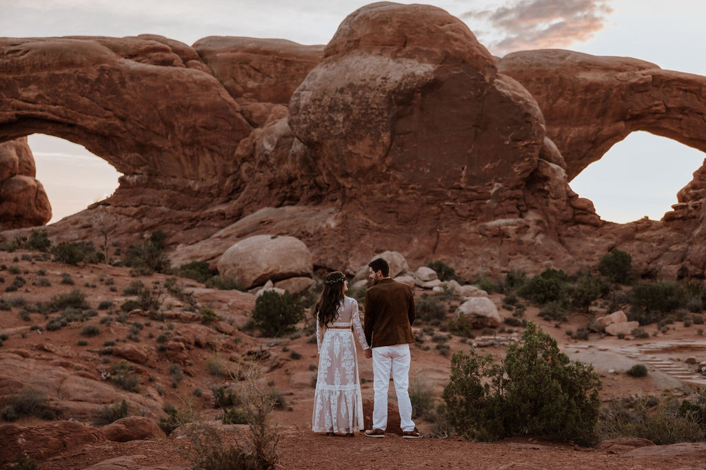 couple holds hands at Arches National Park sunset elopement