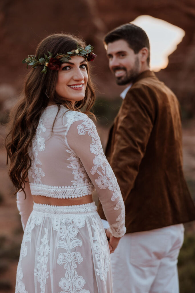 couple walks holding hands at Arches National Park elopement