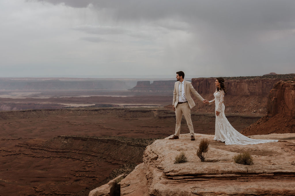 couple holds hands at Canyonlands elopement overlook