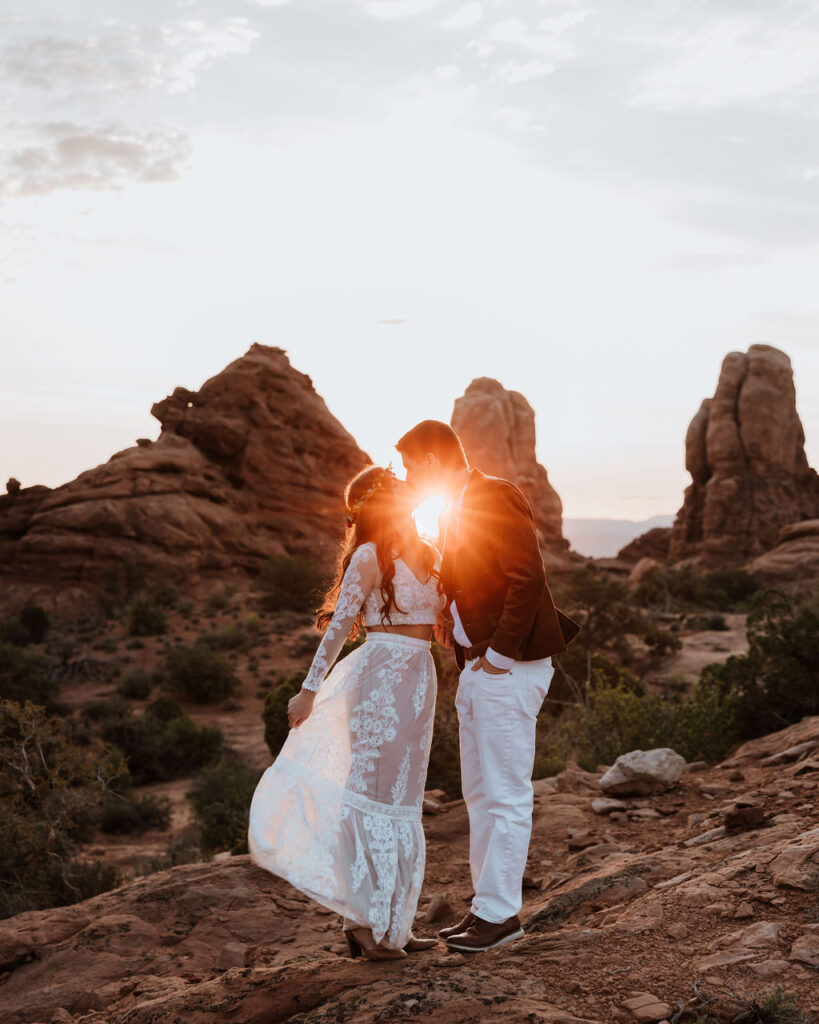 couple kisses at Arches National Park sunset elopement