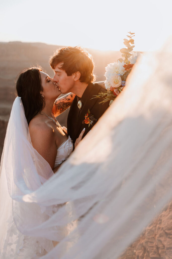 couple kisses under wedding veil