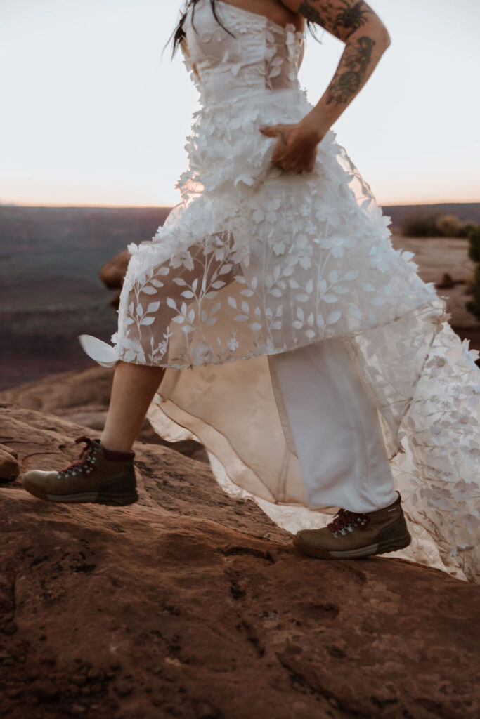 couple walks in wedding dress with hiking boots