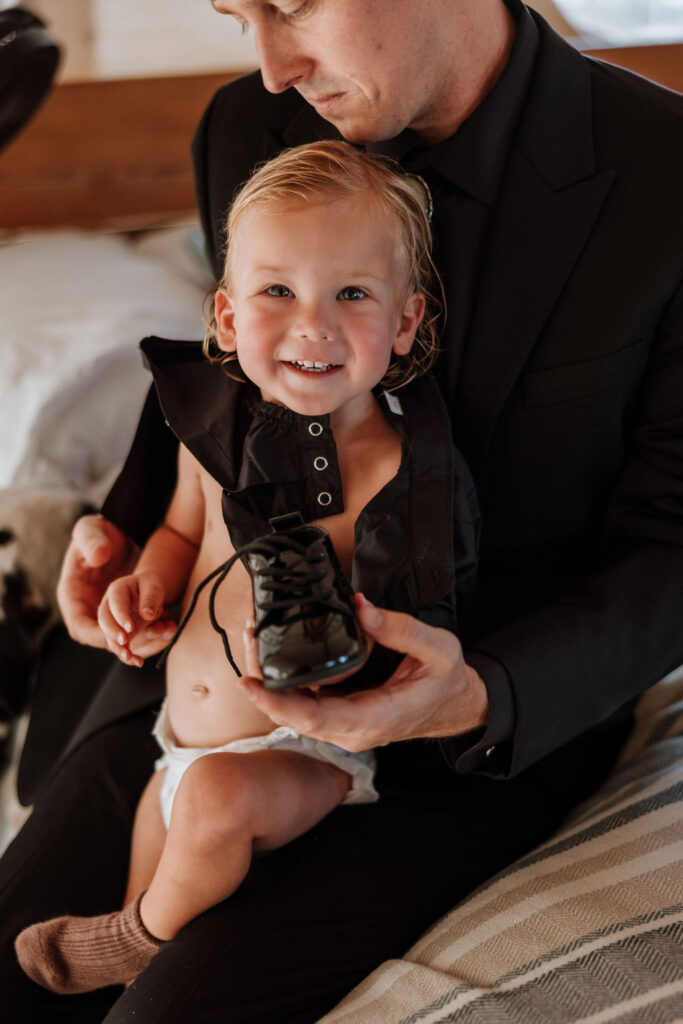 dad holds son dressing him for wedding day