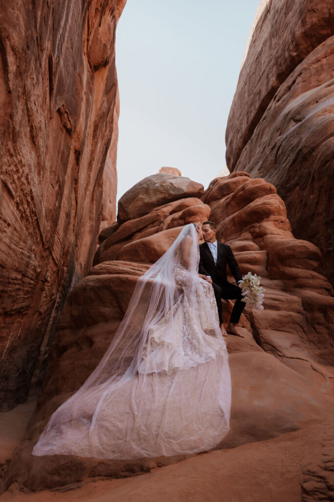 couple kiss on red rock at Moab elopement