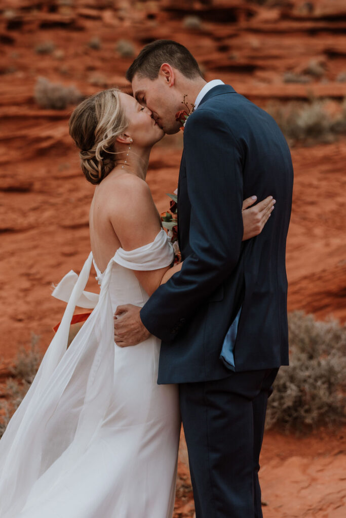 couple kisses at red rock Moab elopement 