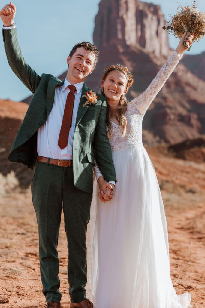 couple cheers with bouquet at Moab outdoor elopement