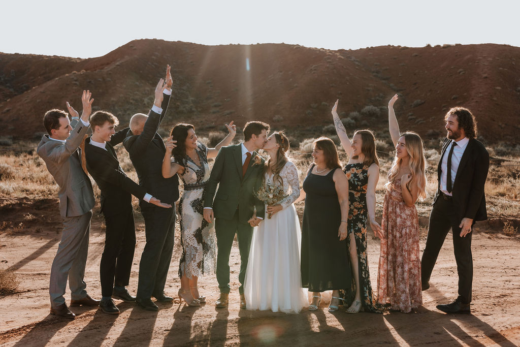 wedding guests cheer while bride and groom kiss