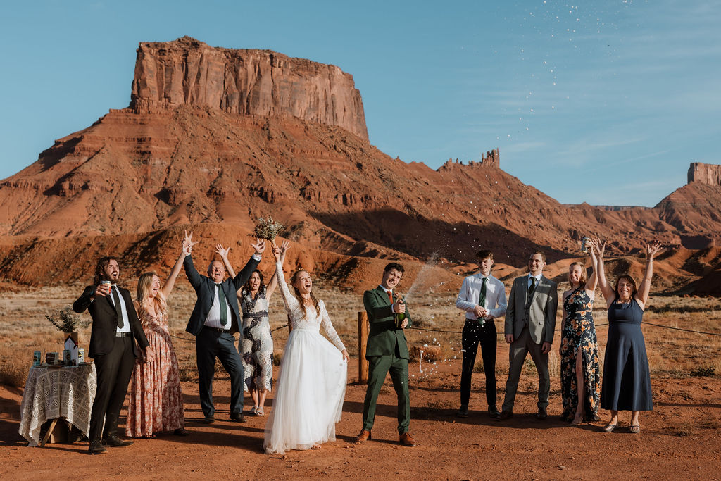 couple pops champagne with guest at BLM land Moab Utah elopement