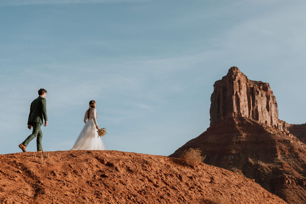 couple walks along ridge at BLM land Moab Utah elopement