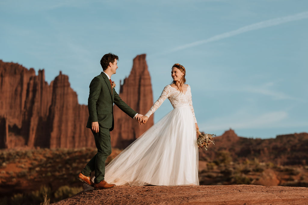 couple holds hands at Moab desert elopement