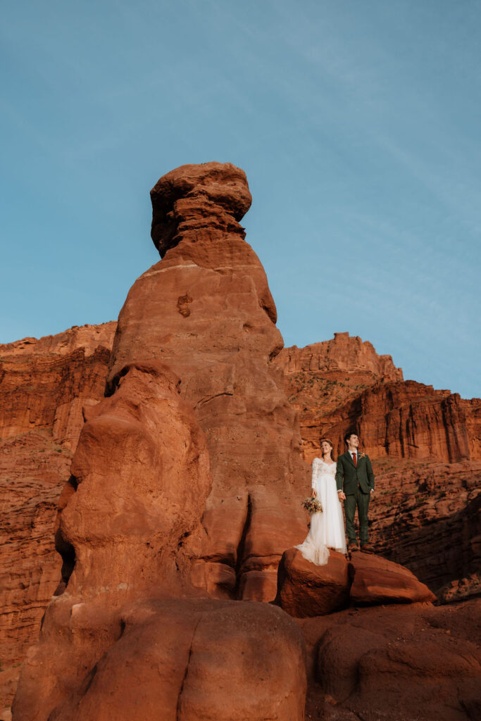 couple poses on rock at red rock Moab elopement