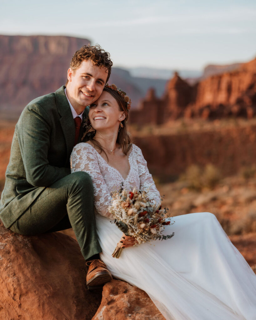 couple sits on rock at red rock Moab elopement