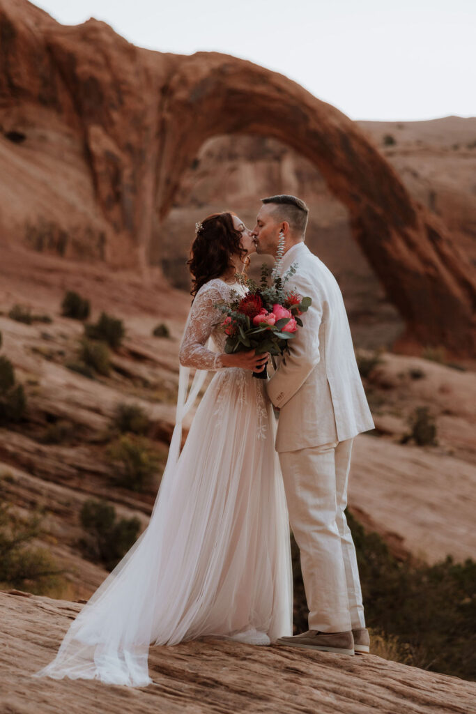 couple kisses at Corona Arch Moab elopement