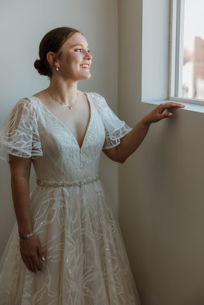 bride poses in front of window during wedding bridal portraits