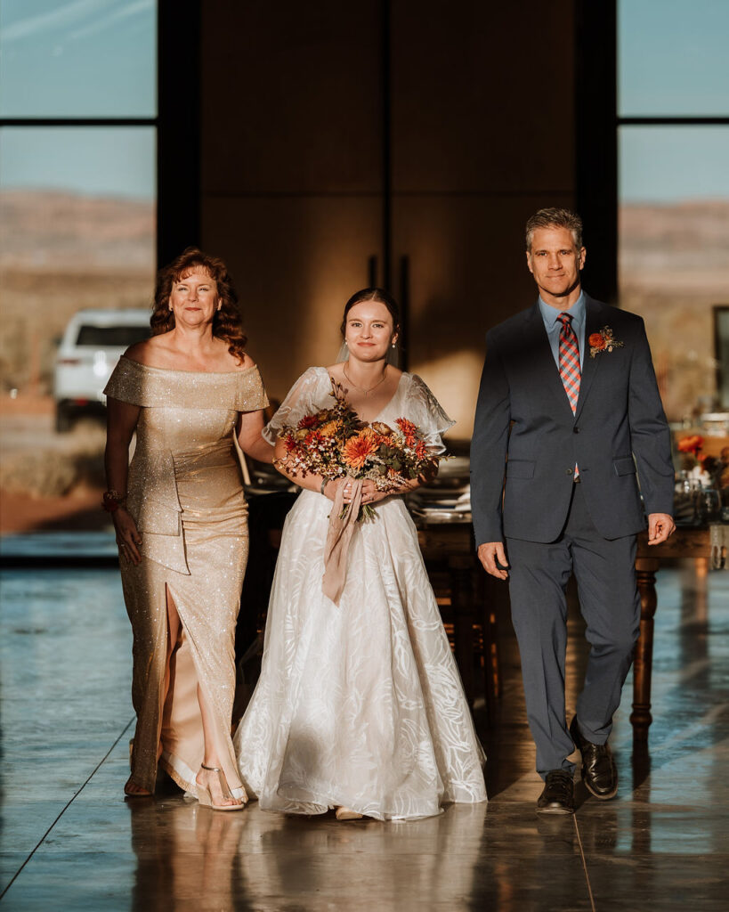 parents walk bride down the aisle at sunset