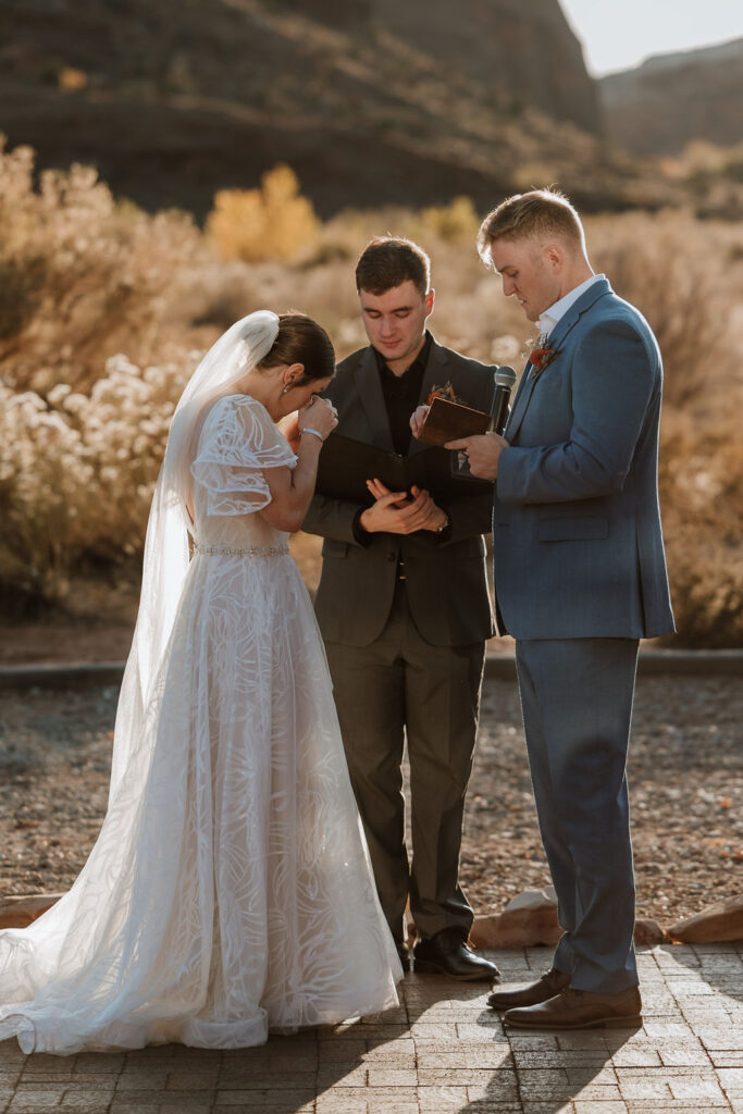 bride wipes away tears during wedding ceremony