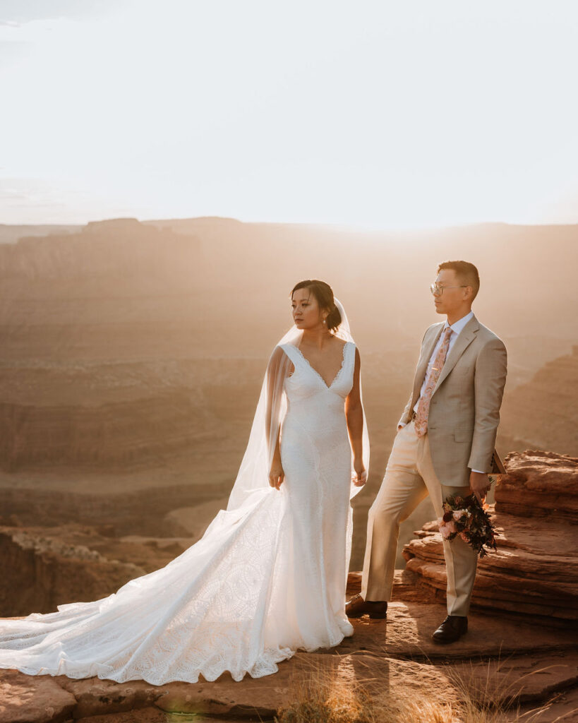 couple poses together at edge of cliff at Moab sunset elopement