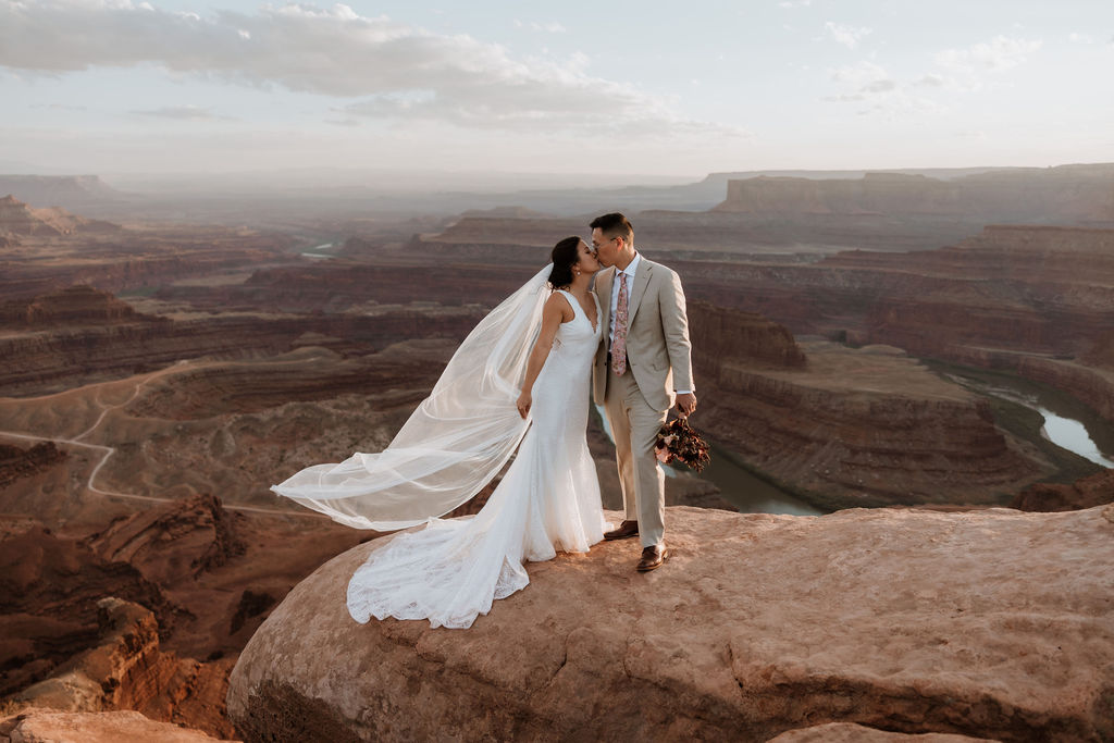 couple kisses on cliff edge at Dead Horse Point elopement