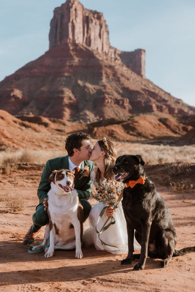 couple kisses with dogs at Castle Valley Moab elopement