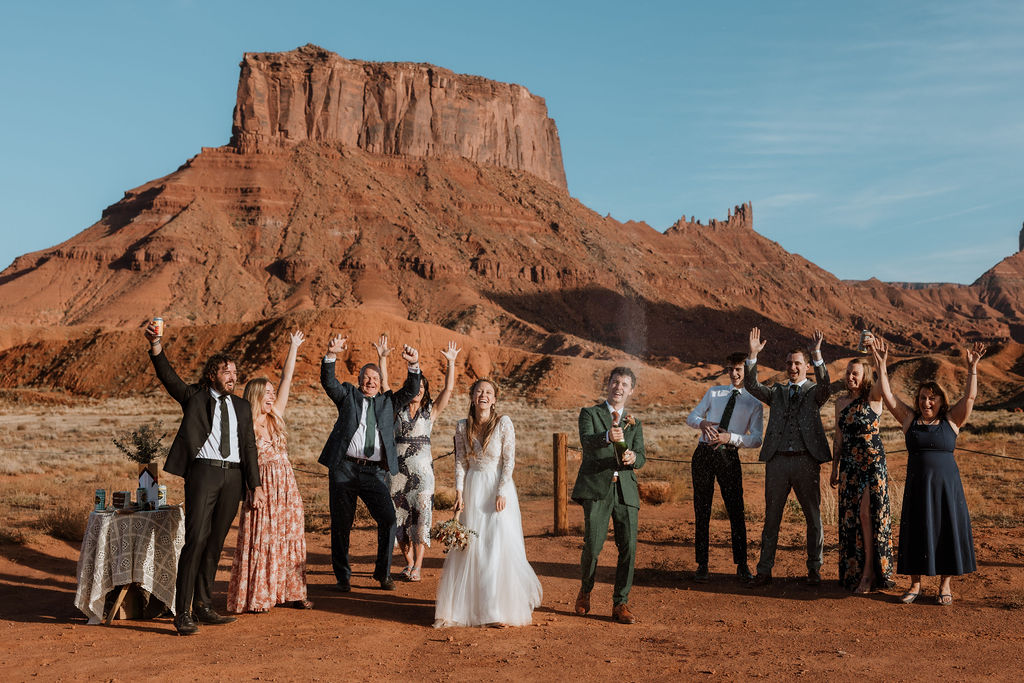 couple pops champagne bottle at Moab elopement