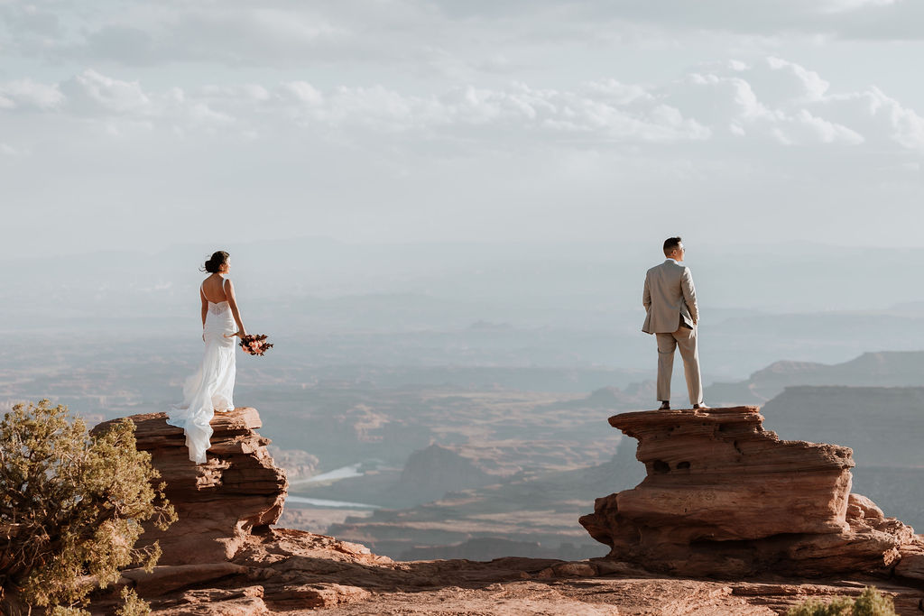 couple poses together at edge of cliff at Moab sunset elopement