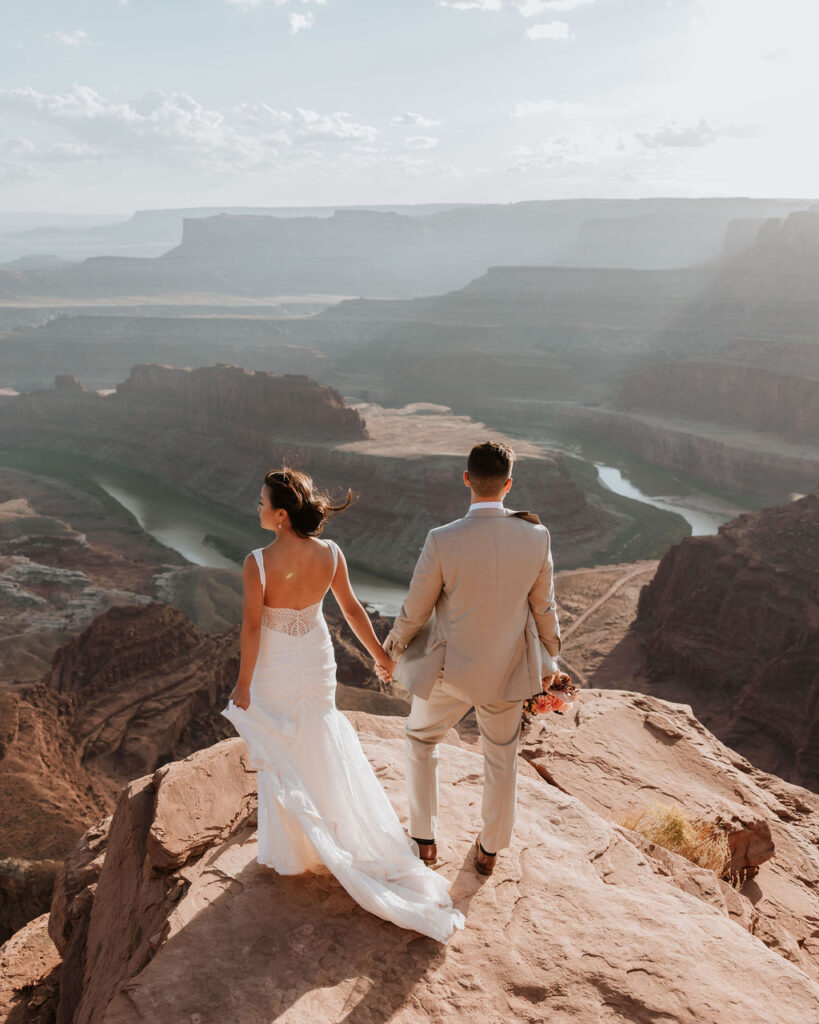 couple holds hands on cliff edge at Dead Horse Point elopement