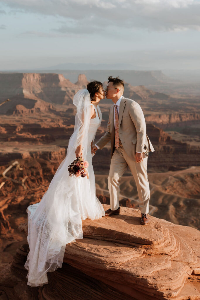 couple kisses on cliff edge at Dead Horse Point elopement