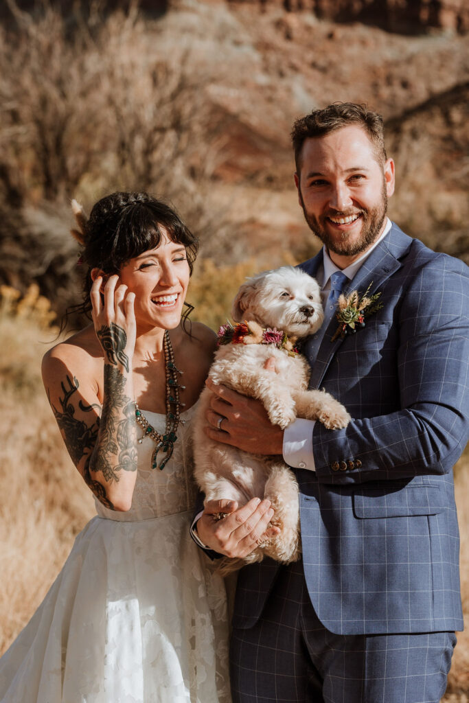 couple poses with dog at Moab desert elopement