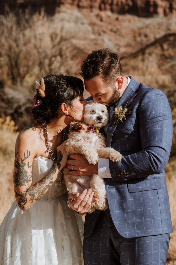 couple poses with dog at Moab desert elopement