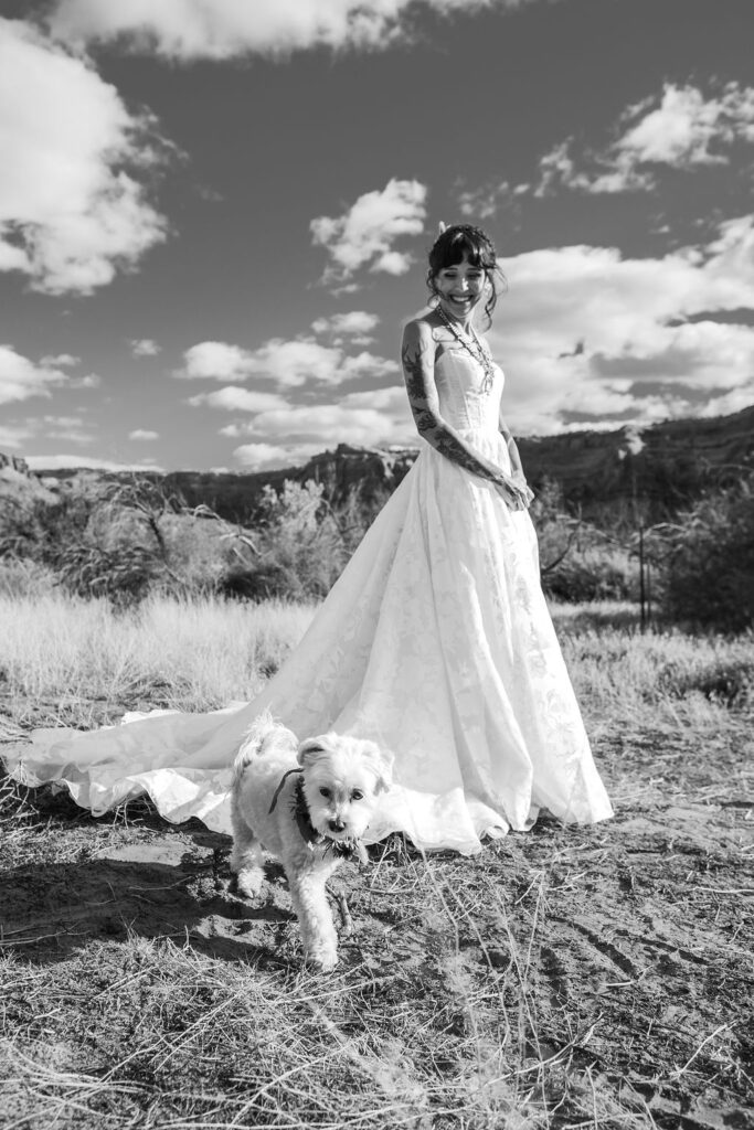 bride poses with dog at desert wedding