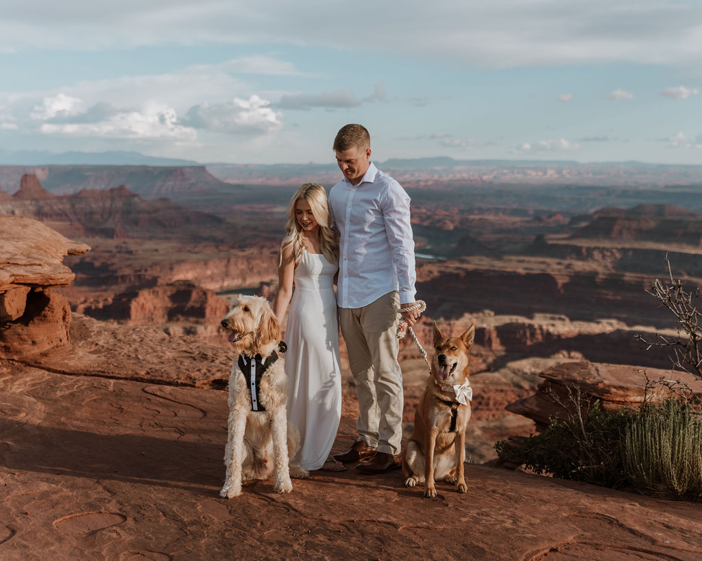 couple poses with dogs at Dead Horse Point State Park