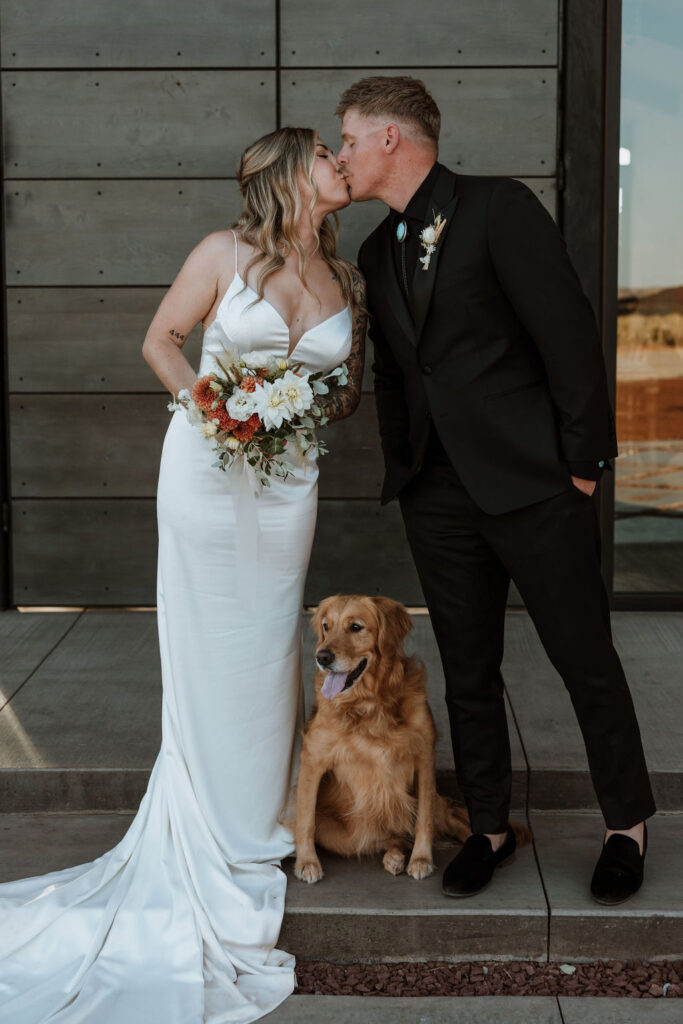 couple kisses with dog at wedding