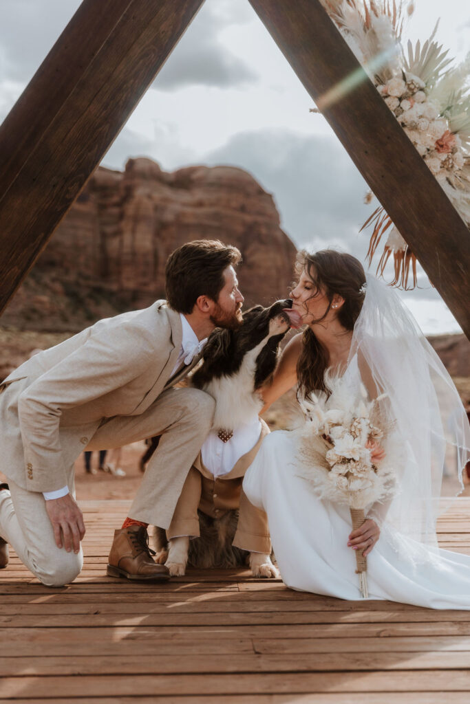 dog kisses bride and groom at Moab desert wedding