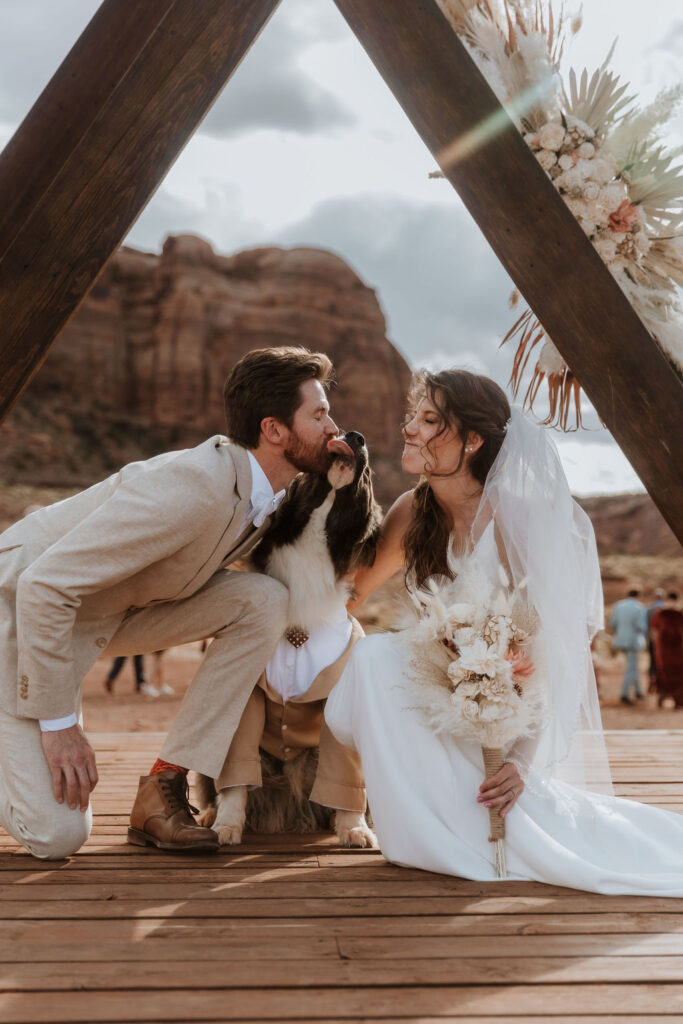 couple kisses dog at Moab desert wedding