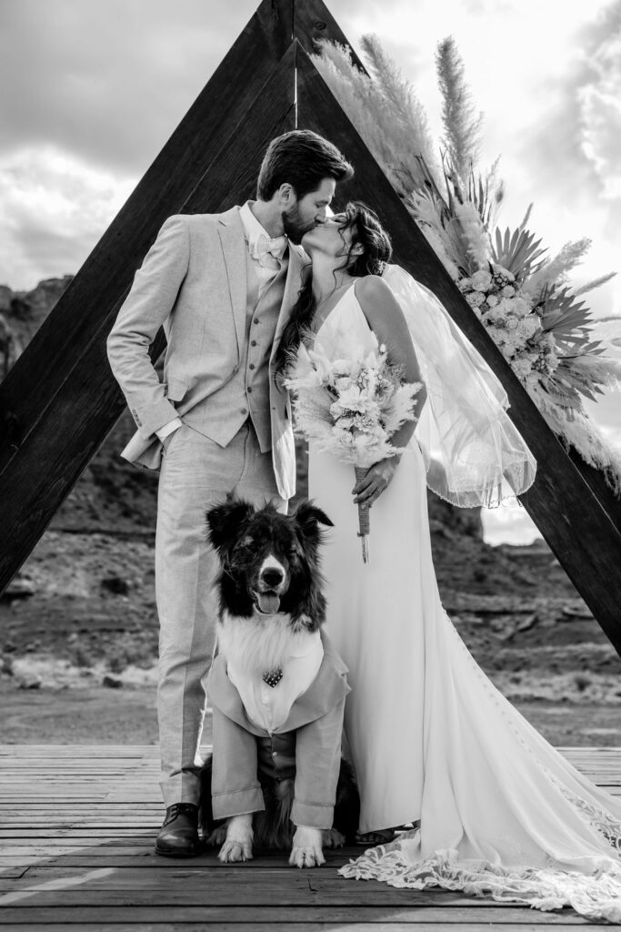 couple kisses with dog at Moab elopement