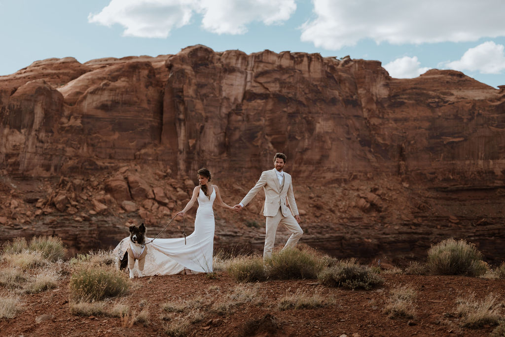 couple walks with dog at Moab elopement