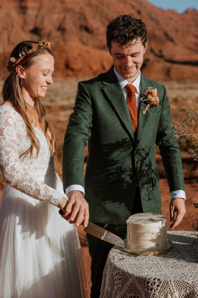 Bride and groom cut into their wedding cake at their desert elopement