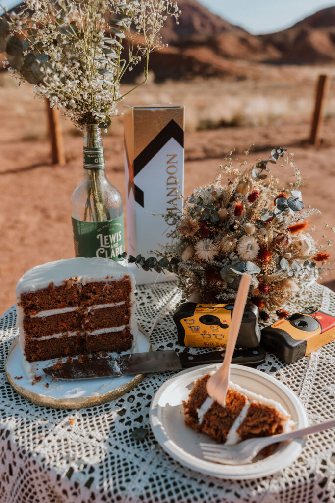 Small table scape set up in the desert with cake an disposable cameras