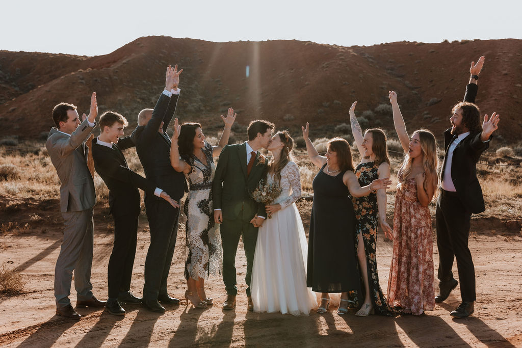 Couple embraces in a kiss while their friends and family cheer them on