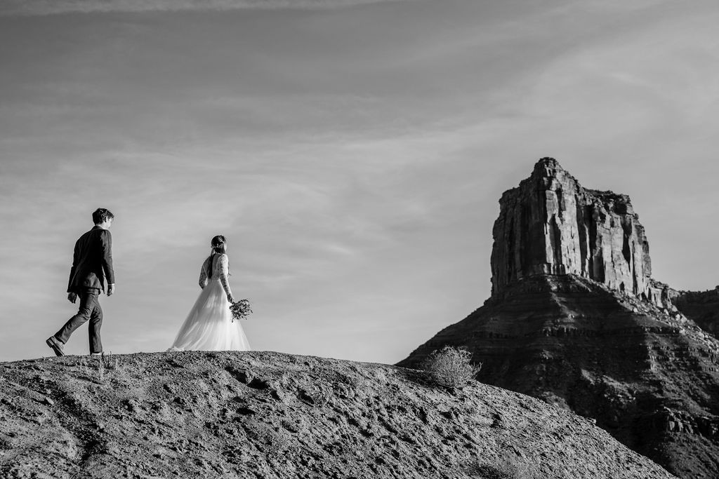 Couple walks across the canyon at Castle Valley Utah Elopement