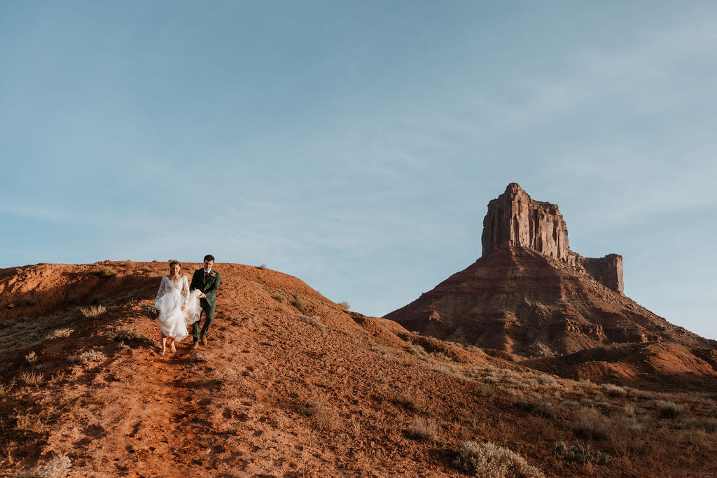 Couple walks down a valley at dessert elopement in Castle Valley