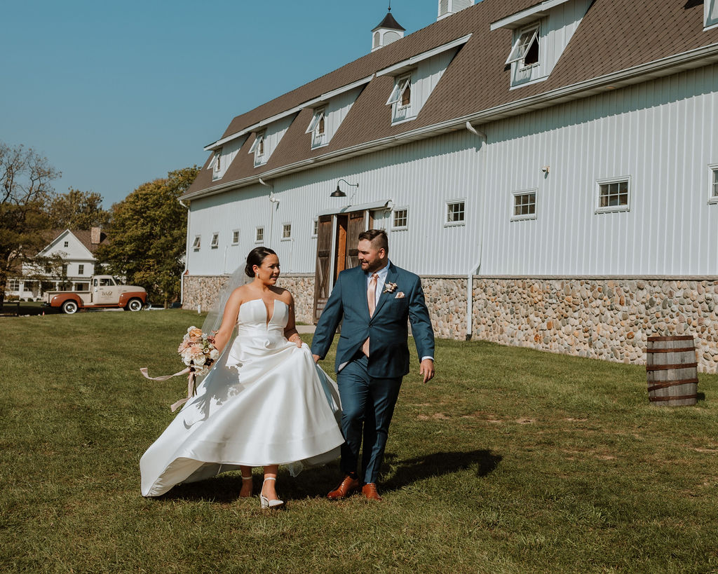 couple runs across field at barn wedding