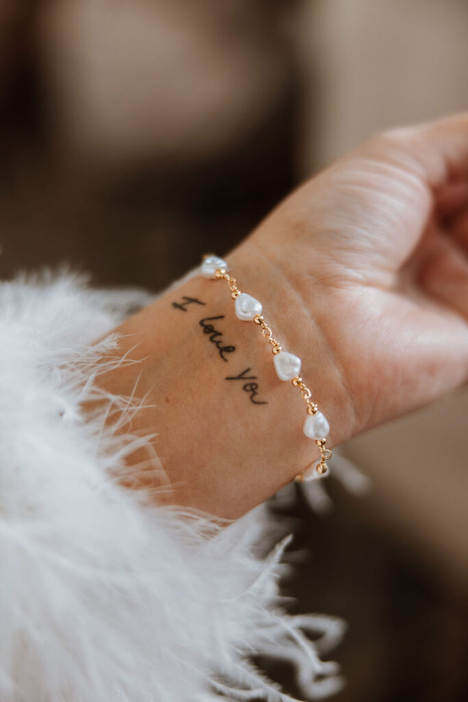 I love you tattoo and pearl necklace on bride's wrist
