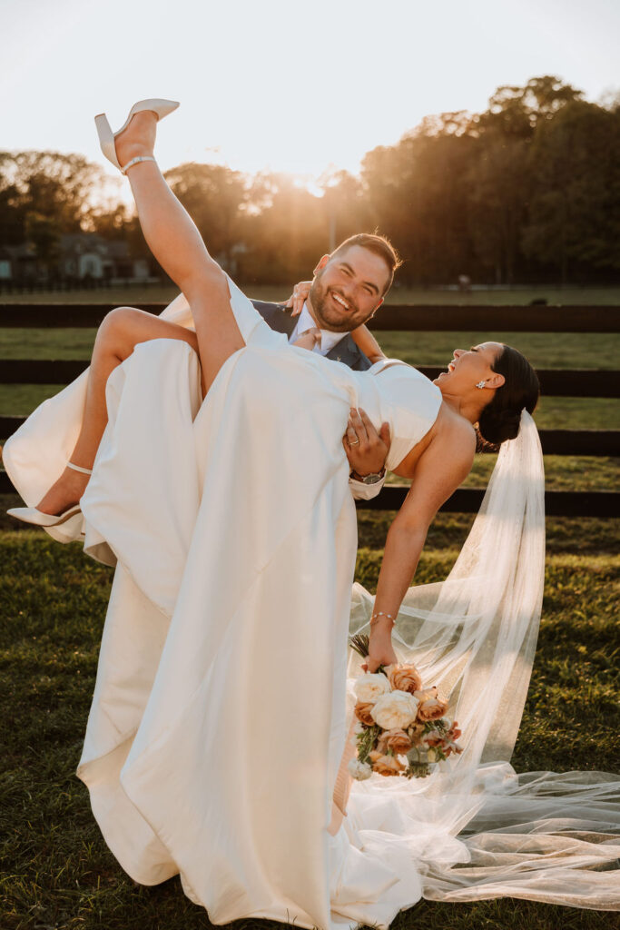 groom holds up bride laughing