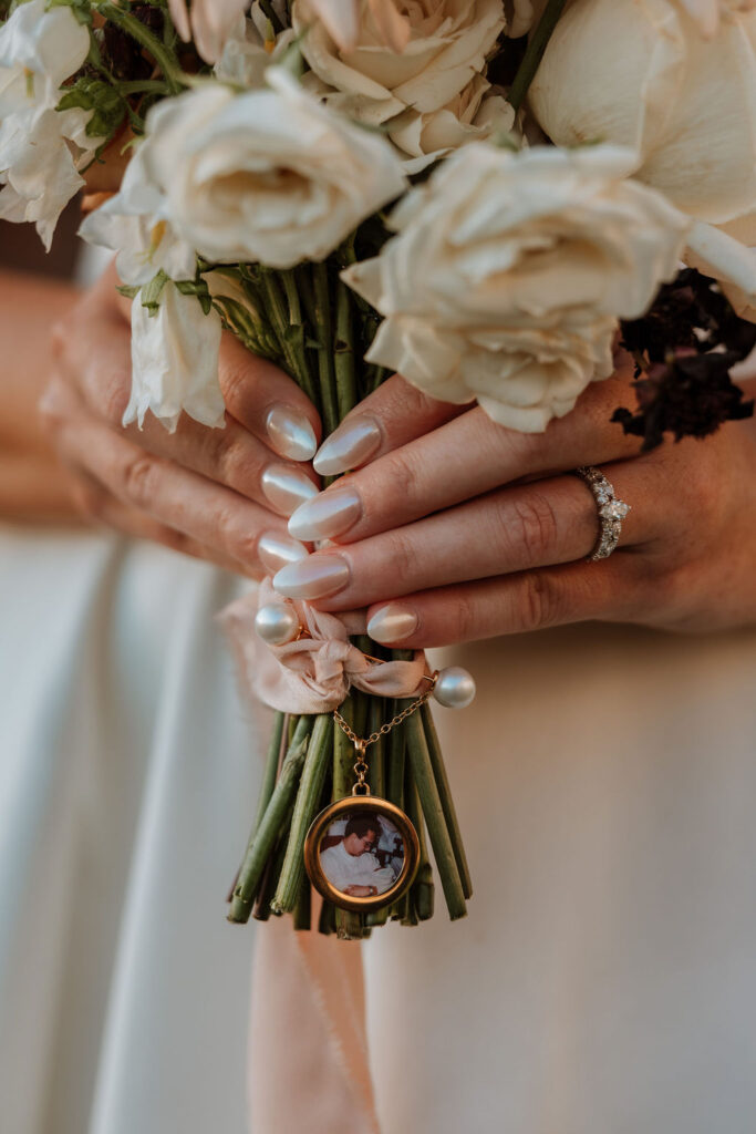 bride holds wedding bouquet with charm attached