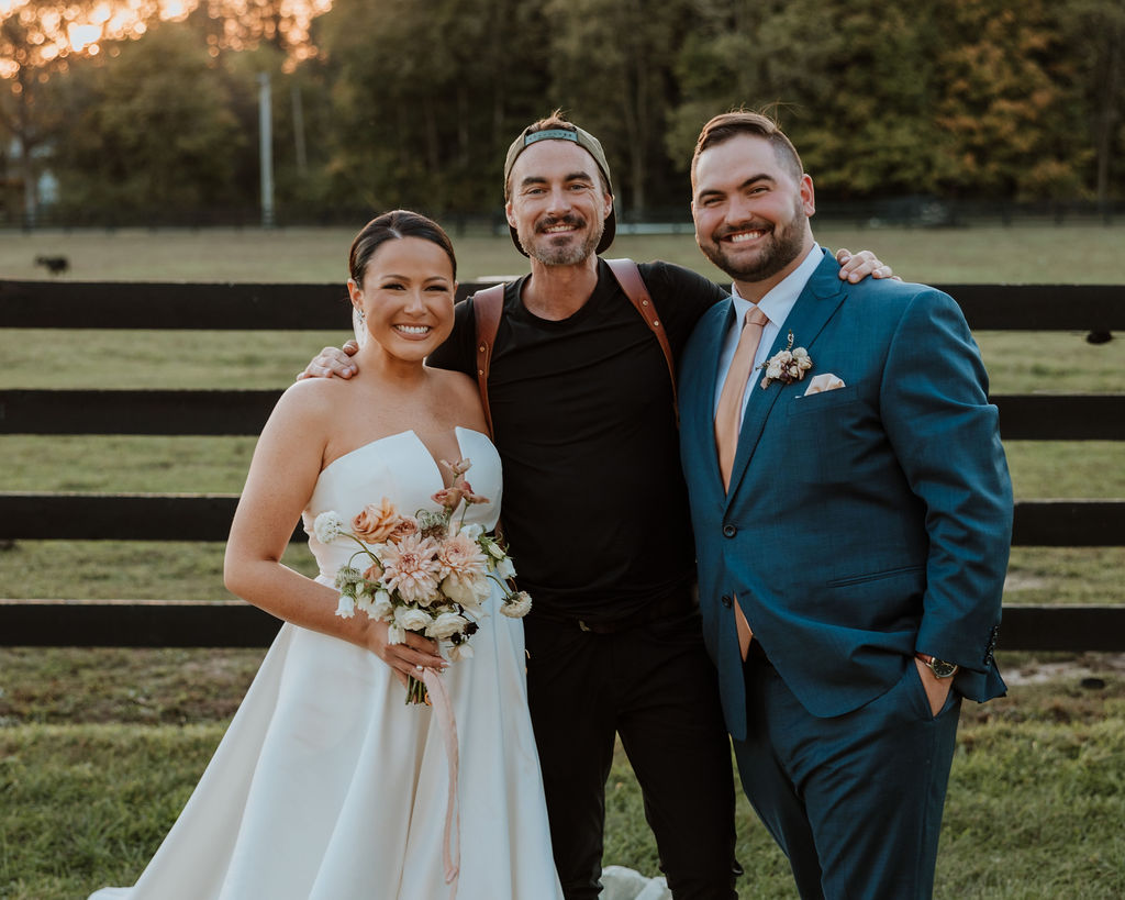 photographer poses with bride and groom 