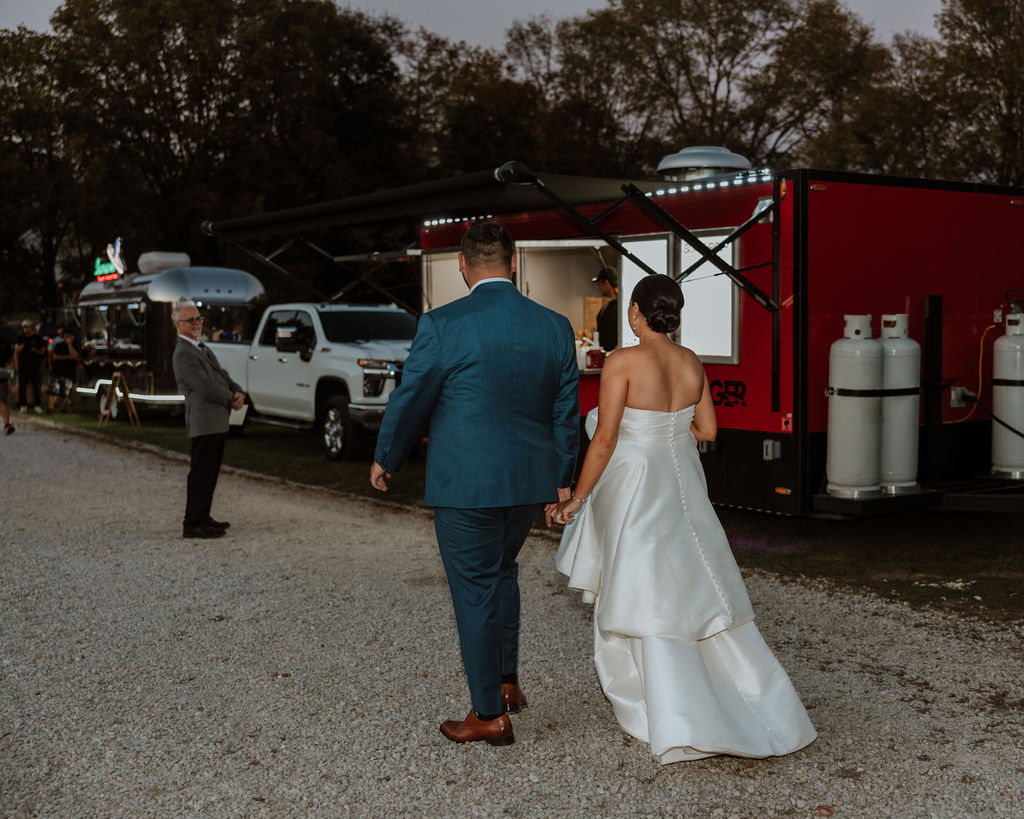 couple walks to food trucks at wedding reception