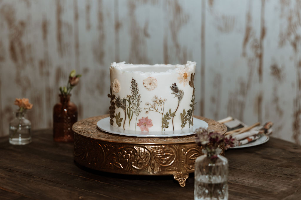 white cake with florals on gold stand