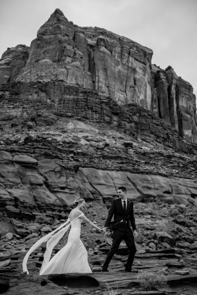 couple walks along red rocks at Dead Horse Point State Park